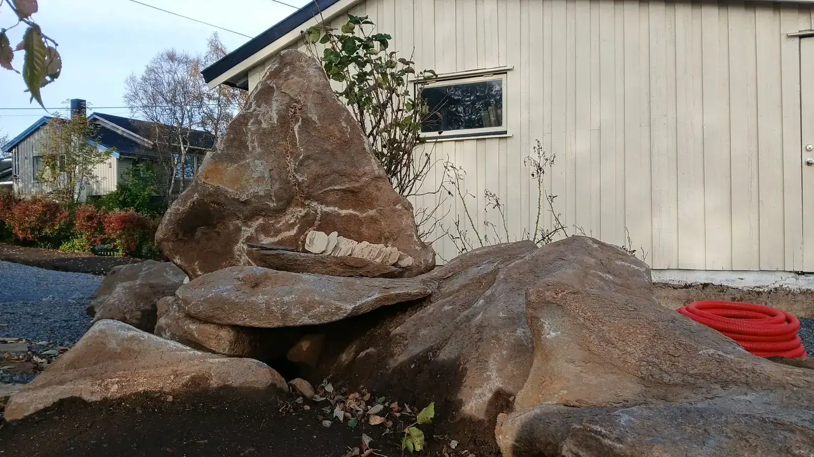 Natursteinparti av store steinblokker og skifer ved siden av bygning