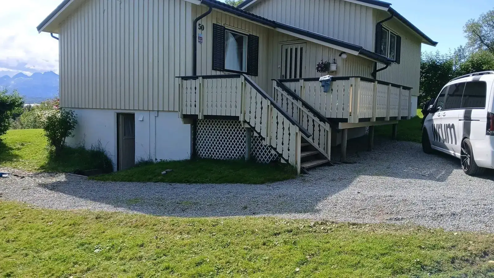 Bolig med terrasse, plen og grusbelagt flate foran huset